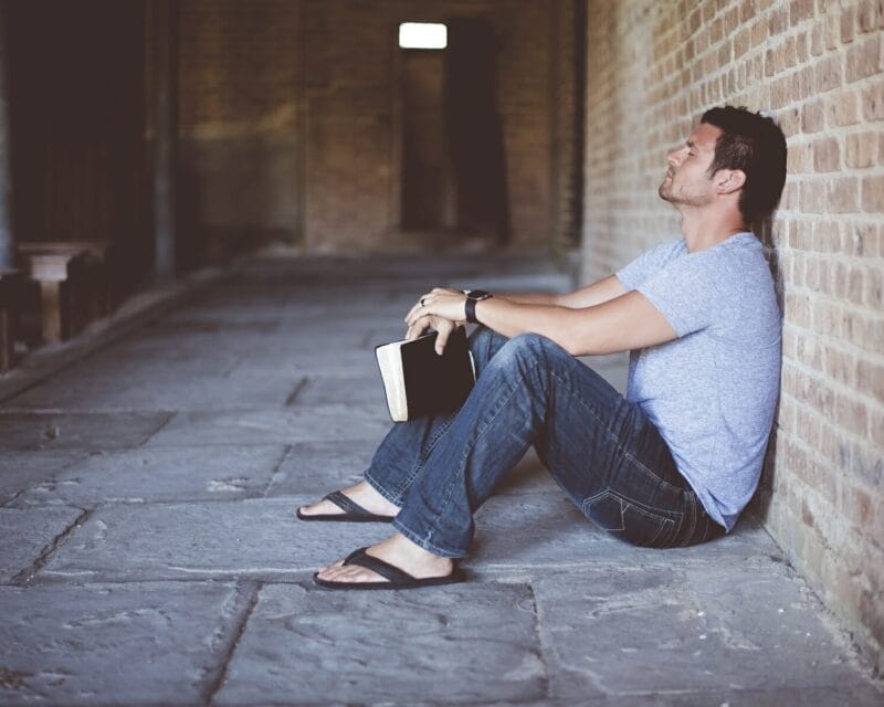 Man holding book frustrated against wall.